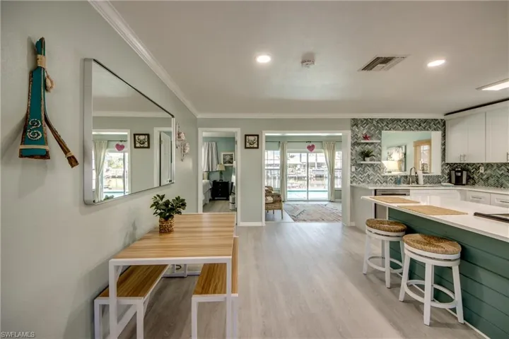 Kitchen featuring backsplash, white cabinets, a healthy amount of sunlight, and light wood-type flooring