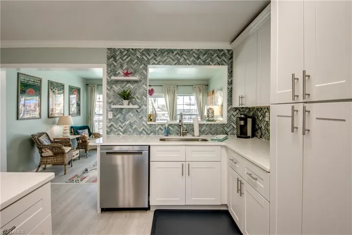 Kitchen with white cabinets, dishwasher, sink, and light hardwood / wood-style flooring