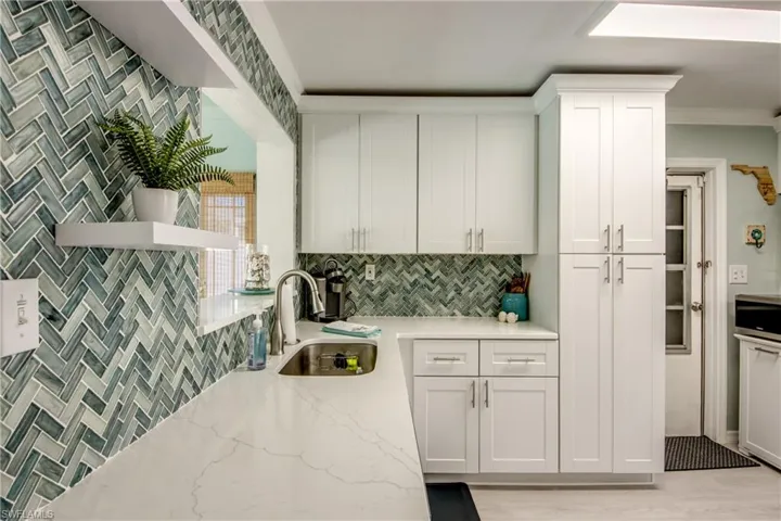 Kitchen featuring white cabinets, light wood-type flooring, light stone counters, and sink