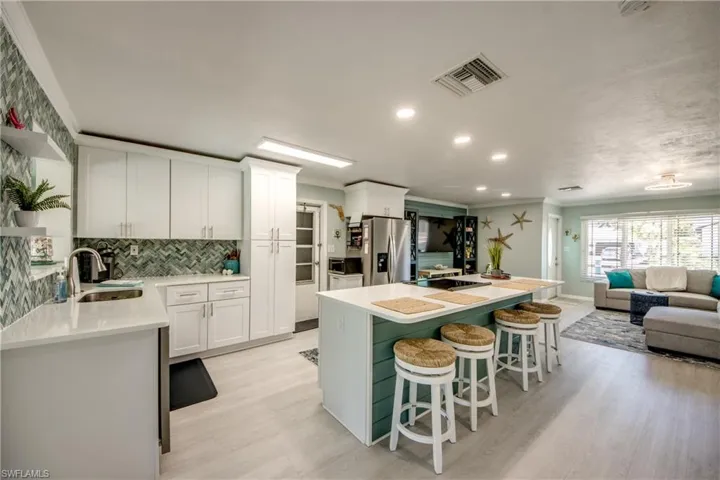 Kitchen featuring backsplash, white cabinets, sink, light hardwood / wood-style flooring, and appliances with stainless steel finishes