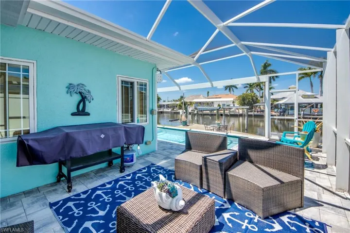 View of patio with a boat dock, a water view, a lanai, and a grill