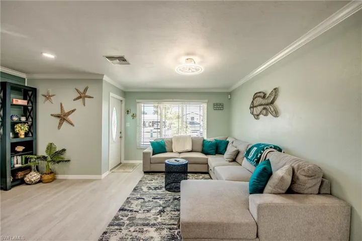 Living room with crown molding and light hardwood / wood-style flooring