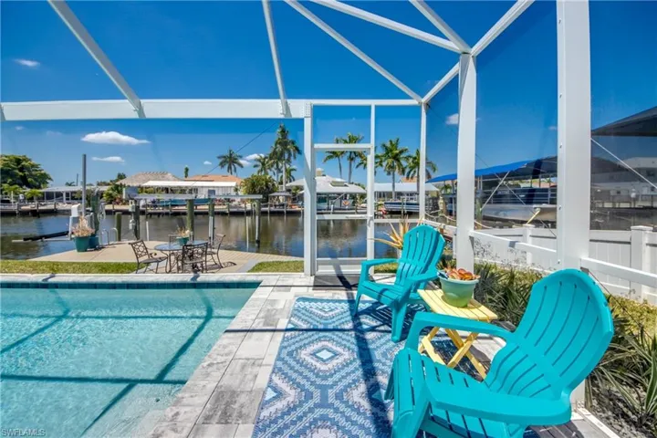 View of pool featuring a patio, a water view, and glass enclosure