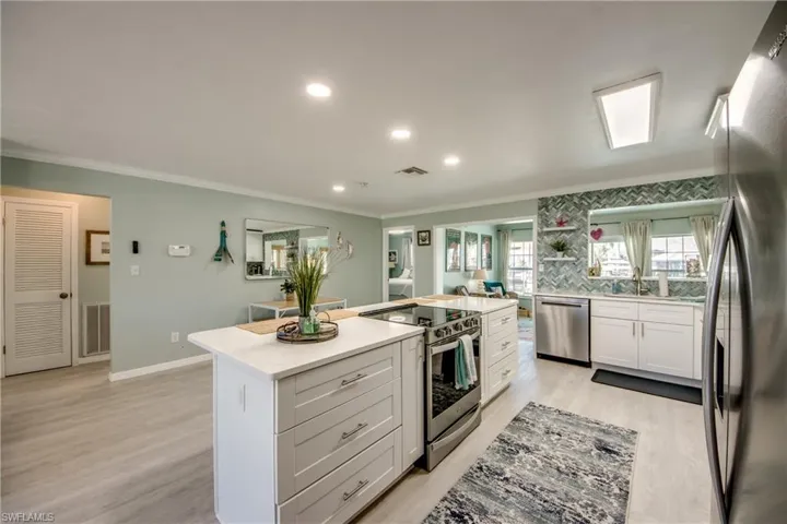 Kitchen featuring a center island, white cabinets, crown molding, light hardwood / wood-style flooring, and stainless steel appliances