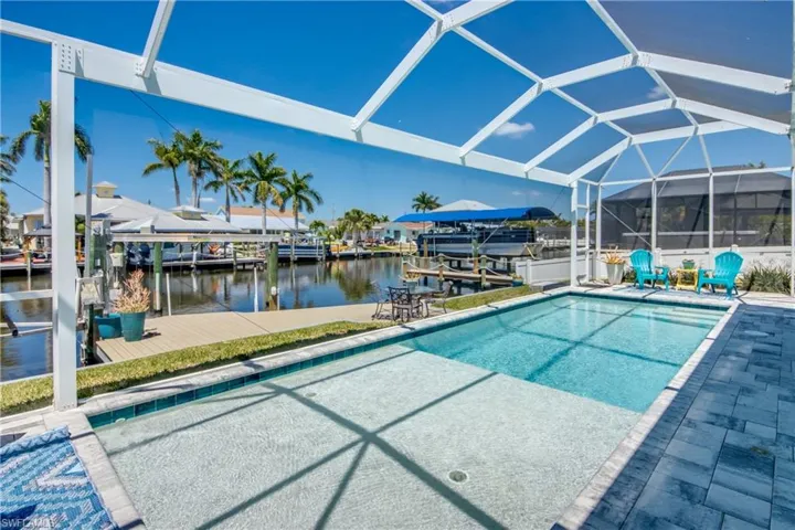 View of swimming pool with glass enclosure, a water view, and a dock