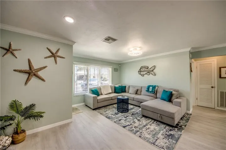 Living room featuring crown molding and light hardwood / wood-style flooring