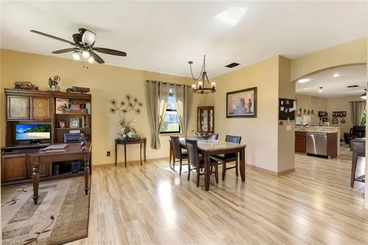 Dining room featuring a ceiling fan, arched walkways, light wood-style floors, and a chandelier