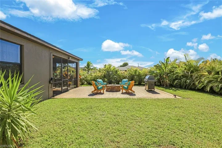 View of green lawn featuring a patio area, an outdoor fire pit, and a sunroom