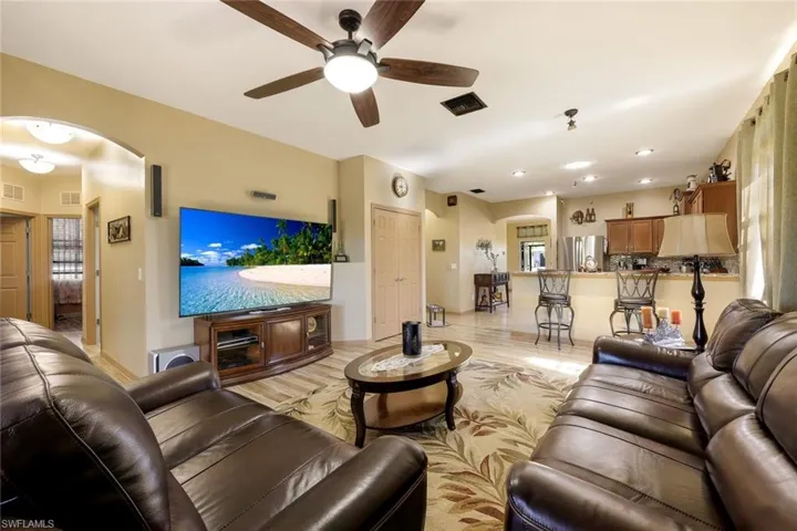 Living area featuring arched walkways, light wood-style floors, ceiling fan, and recessed lighting