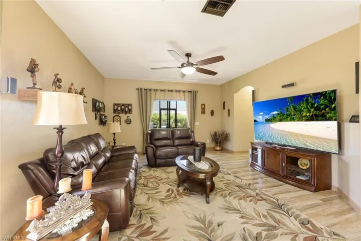 Living area featuring light wood-style floors, a ceiling fan, and arched walkways