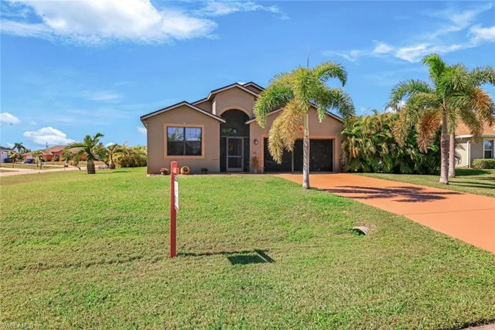 View of front of house with concrete driveway, stucco siding, a front yard, and an attached garage