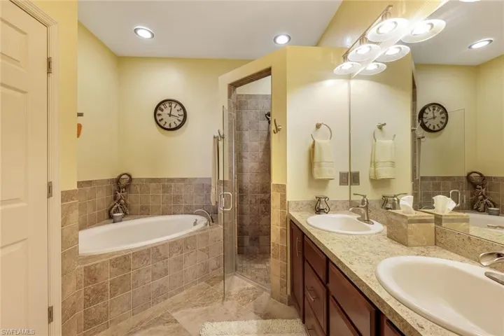 Bathroom with a garden tub, double vanity, a shower stall, and recessed lighting