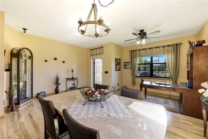 Dining space featuring light wood-type flooring, a chandelier, and a ceiling fan