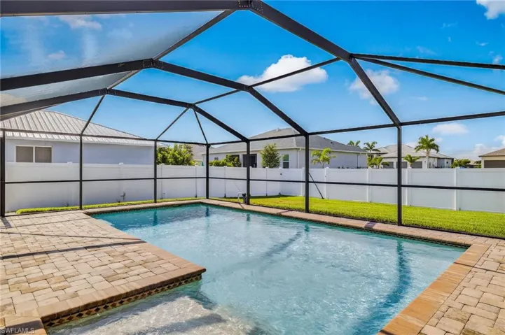 View of swimming pool, screen enclosure and large green space fenced