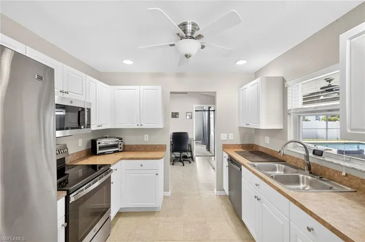 Kitchen with appliances with stainless steel finishes, recessed lighting, white cabinets, ceiling fan, and an office area