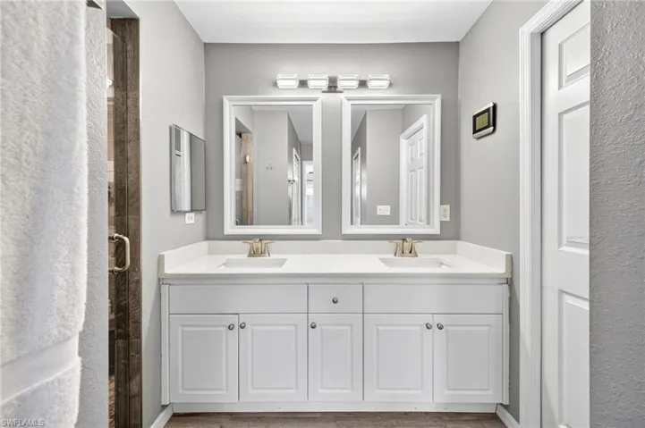 Full Primary remodeled bath, featuring double vanity, a shower, and wood finished floors