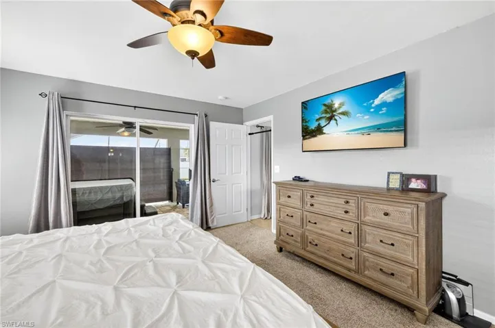 Primary Bedroom with access to exterior, light colored carpet, and ceiling fan