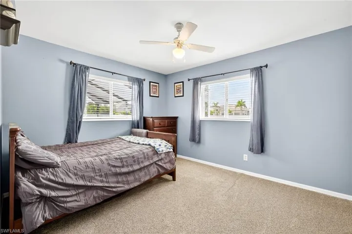 Carpeted bedroom with multiple windows and ceiling fan
