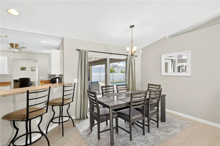 Dining space with a chandelier, vaulted ceiling, recessed lighting, light tile patterned flooring, and ceiling fan