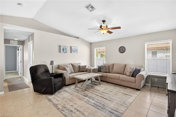 Tiled spacious living room open to kitchen featuring vaulted ceiling and ceiling fan