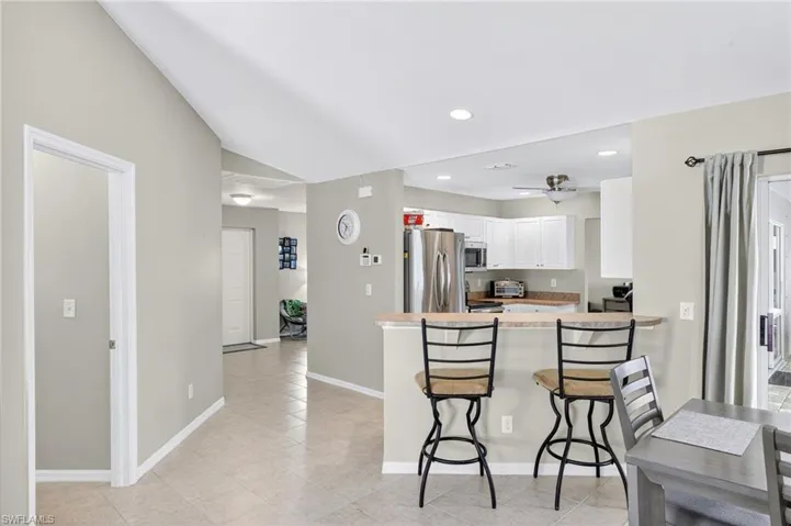 Kitchen with appliances with stainless steel finishes, white cabinetry, a breakfast bar, lofted ceiling, and a peninsula