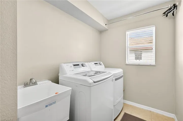 Washroom with washer and clothes dryer and light tile patterned floors