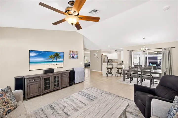 Living area featuring ceiling fan, lofted ceiling, and light tile patterned floors