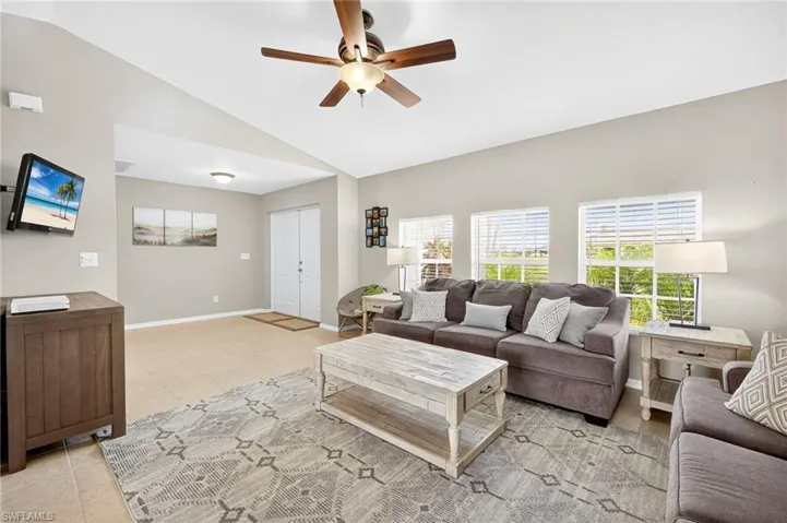 Living area with office area, ceiling fan, vaulted ceiling, and light tile patterned floors