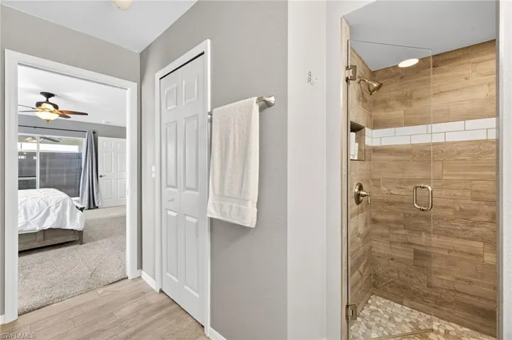 Remodeled Primary Bathroom, featuring a gorgeous tiled shower, a ceiling fan, wood finished floors