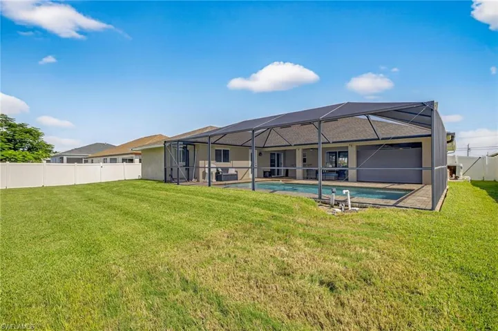 Rear view of property with pool, paver deck and lanai.  LARGE green space beyond pool area.