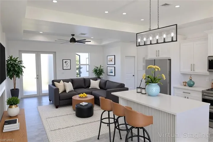 Living area featuring a raised ceiling, a ceiling fan, recessed lighting, and light wood-type flooring
