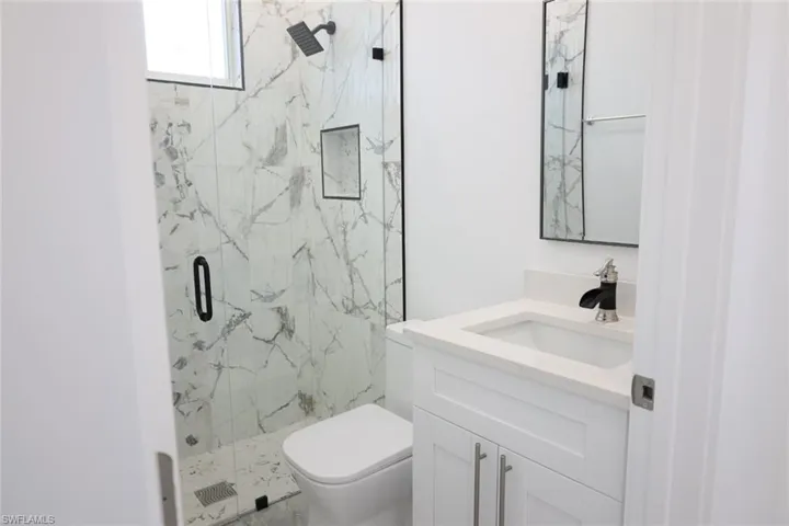 Full bath featuring a marble finish shower and vanity