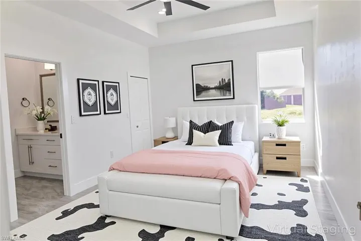 Bedroom with a raised ceiling, light wood-type flooring, ceiling fan, and a closet