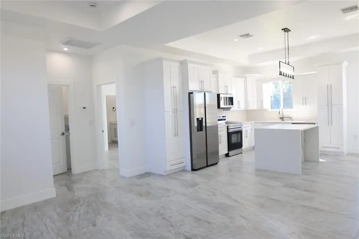 Kitchen with a center island, stainless steel appliances, white cabinets, and a raised ceiling