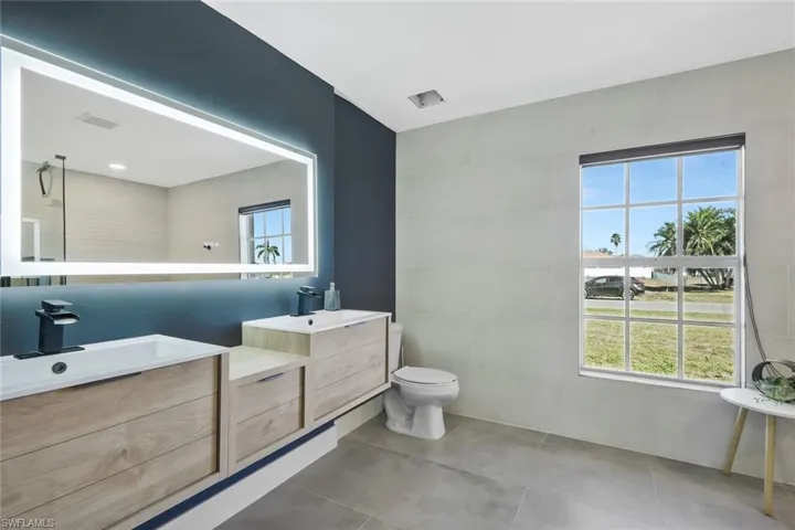 Full bathroom featuring double vanity, tile walls, and light tile patterned flooring