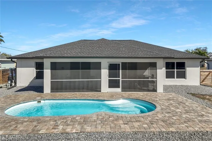 Back of property featuring stucco siding, roof with shingles, an outdoor pool, and a patio