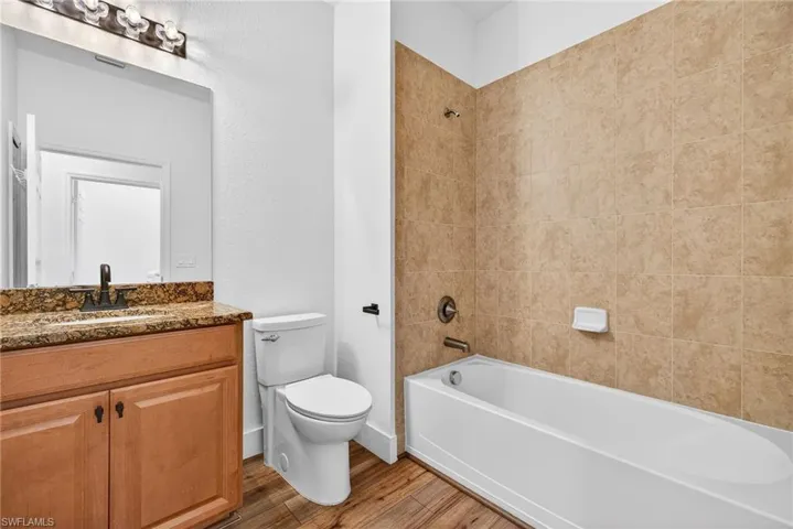 Bathroom featuring washtub / shower combination, vanity, and wood finished floors