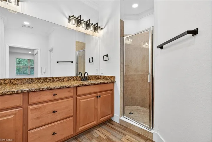 Full bathroom featuring a stall shower, ornamental molding, vanity, light wood-type flooring, and recessed lighting