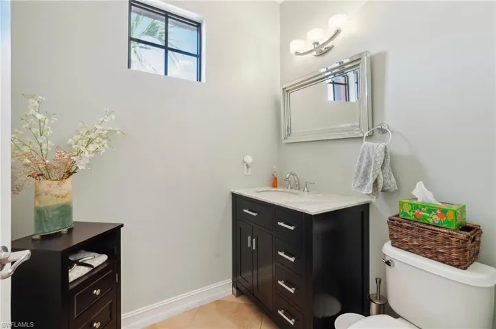 Bathroom featuring vanity, baseboards, tile patterned floors, and toilet