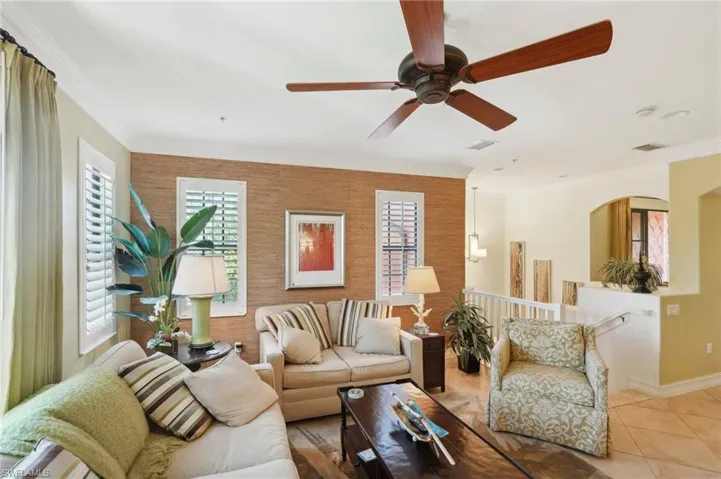 Living room with visible vents, baseboards, ceiling fan, and tile patterned floors