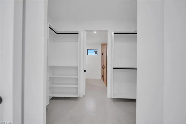 Walk-in closet with built-in shelving, hanging rods, and light-toned flooring