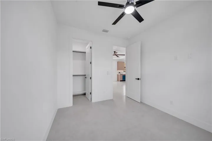 Room featuring light-toned flooring, white walls, and a modern ceiling fan with integrated lighting