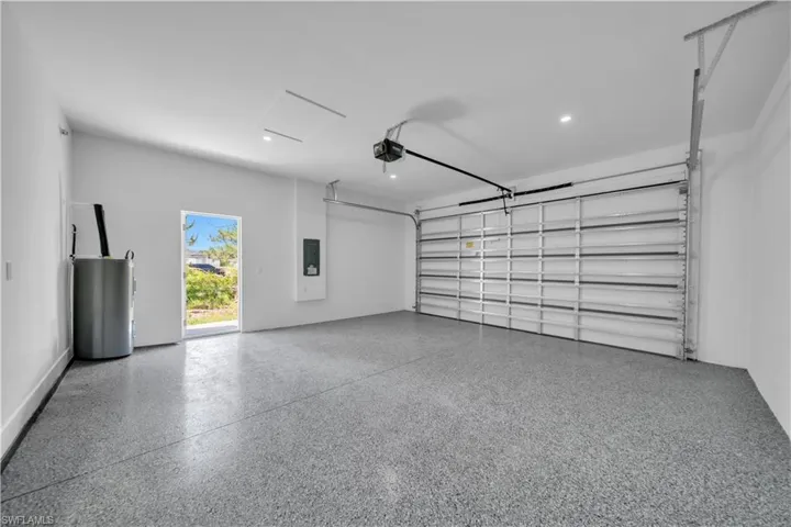 Spacious garage featuring a durable epoxy-coated floor, automatic overhead door, and recessed lighting