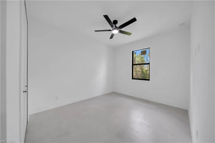 Contemporary room featuring a black ceiling fan with integrated lighting, a single window with black trim, and light-toned flooring