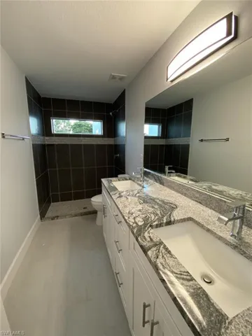 Bathroom featuring vanity, a textured ceiling, a tile shower, tile patterned floors, and toilet