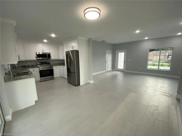 Kitchen featuring white cabinets, sink, appliances with stainless steel finishes, dark stone countertops, and light hardwood / wood-style floors