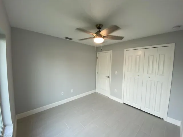 Unfurnished bedroom with ceiling fan and a closet