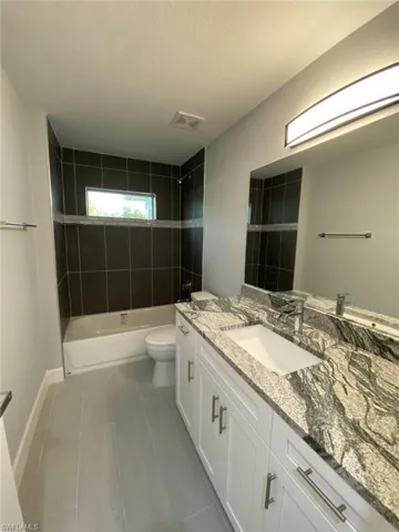 Full bathroom featuring a textured ceiling, tiled shower / bath combo, tile patterned floors, vanity, and toilet