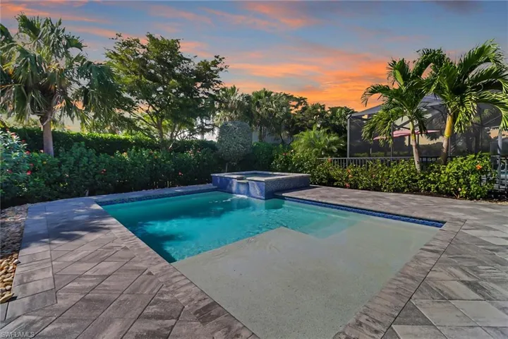 Pool at dusk featuring a hot tub w/ water fall overflow