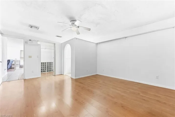 Virtually Unfurnished living room featuring arched walkways, ceiling fan, light wood finished floors, and a textured ceiling